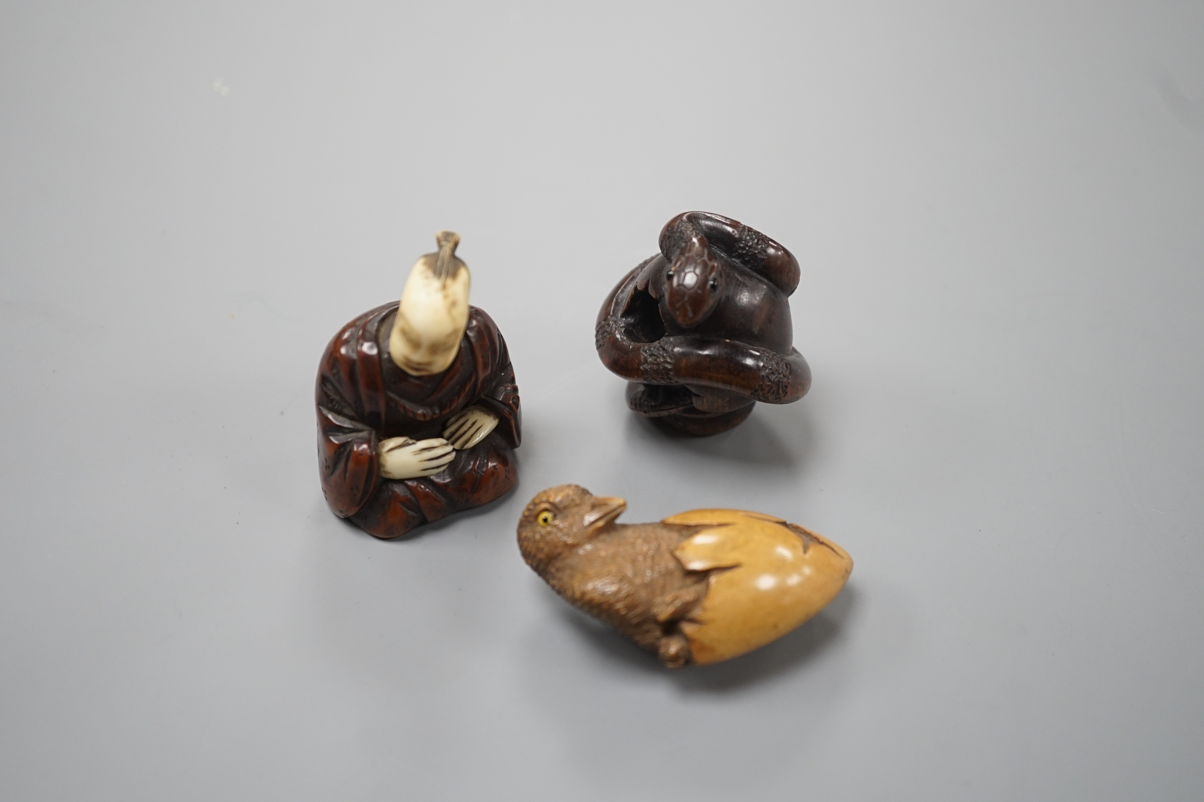 A Continental wood ‘chick and egg’ brooch ivory, 5.3cm, a Japanese ivory and wood figure and a wood netsuke of snakes (3)